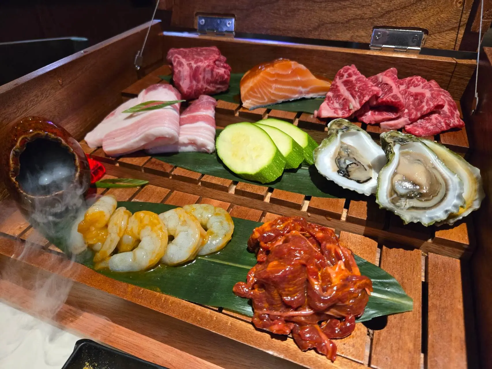 Daruma-BBQ & Sushi-AYCE-Asian-Restaurant-Daruma-Assorted-BBQ-&-Sushi-Box-Holyoke Assorted BBQ meats and sushi in a wooden box with shrimp, oysters, salmon, and marinated beef at Daruma BBQ & Sushi AYCE, a Asian Restaurant in Holyoke