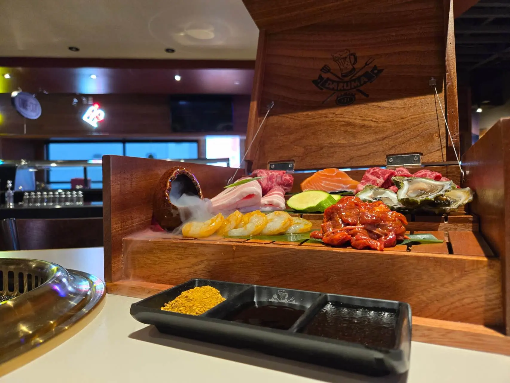 Deluxe BBQ and sushi platter in a wooden box with dry ice, featuring shrimp, oysters, salmon, and premium meats at Daruma BBQ & Sushi AYCE, a Asian Restaurant in Holyoke